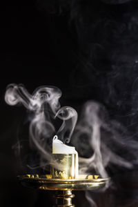 Close-up of smoke emitting from candle against black background