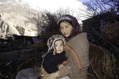 Portrait of mother with daughter sitting outdoors during winter