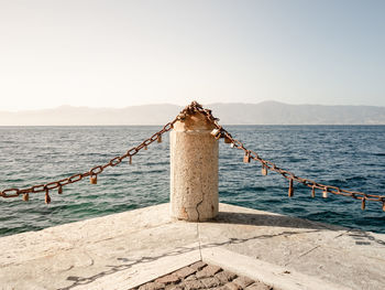 Wooden post on pier by sea against sky