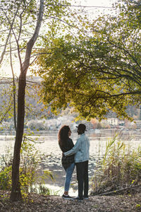 Side view of romantic couple standing at lakeshore
