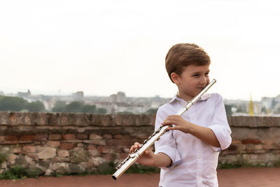 Cute little flautist playing music outdoors.