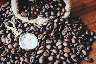 Pocket watch on roasted coffee beans at table