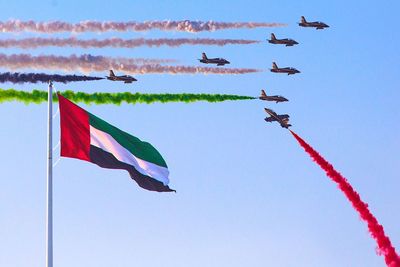 Low angle view of airshow over united arab emirates flag against clear sky