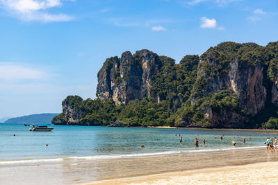 People at beach against mountain