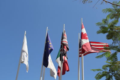 Low angle view of flags against clear blue sky