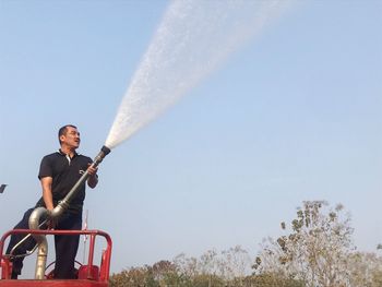 Man holding hose against sky