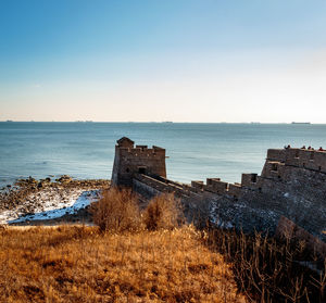 Abandoned rusty by sea against clear sky at sunset