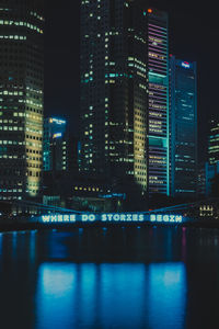 Illuminated buildings by river at night