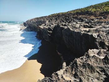 Rock formation on beach against clear sky