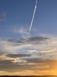 Low angle view of vapor trail against sky during sunset