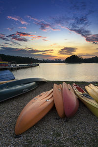 Colorful boats at lakeshore against sky during sunset