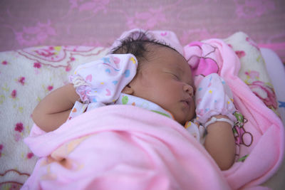 A quiet asian baby is in bed while sleeping in a bright room.