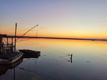 Sailboats moored in lake against sky during sunset