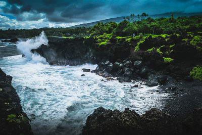 Scenic view of sea by cliff against sky