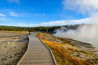 Boardwalk leading towards land against sky