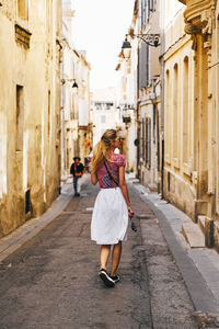 Rear view of woman walking on footpath in city