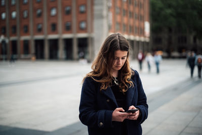 Young woman using mobile phone in city