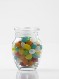 Multi colored candies in jar against white background