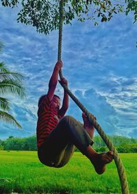 Full length of boy climbing a rope