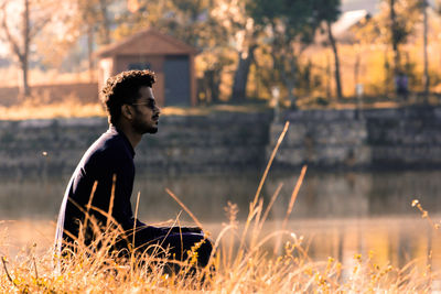 Side view of young man sitting on field