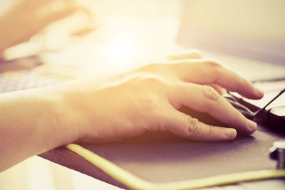 Midsection of woman using computer mouse at desk