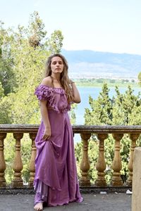 Portrait of woman standing by railing against trees