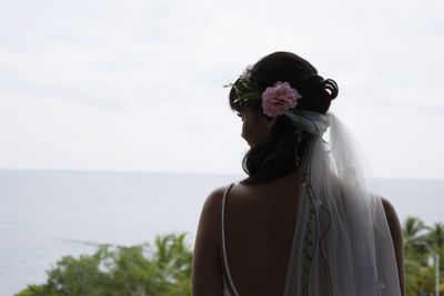 Woman standing on rock by sea against sky