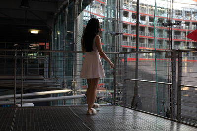 Rear view of woman walking on floor by railings