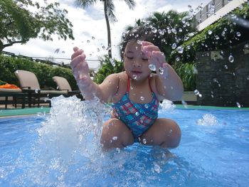 Close-up of girl splashing water in swimming pool