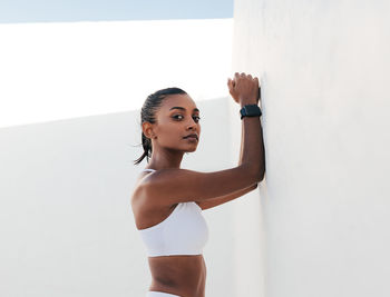 Young woman exercising against wall