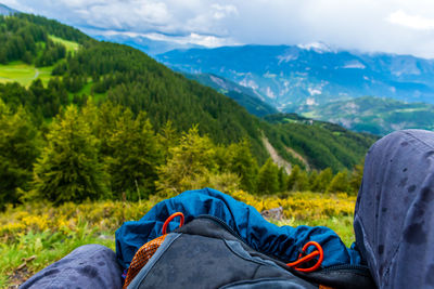 A first-person pov shot of a hiker sitting with a backpack while it's raining in the french alps