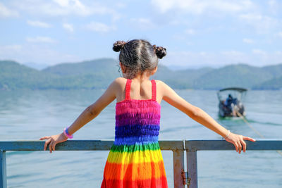 Rear view of girl wearing colorful dress while looking at lake