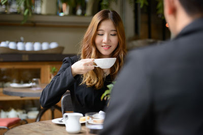 Young woman drinking coffee while sitting in cafe