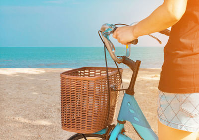 Midsection of woman with bicycle at beach