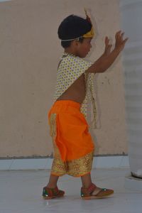 Side view of a girl standing against wall