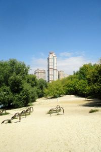 Trees and buildings in city against clear sky