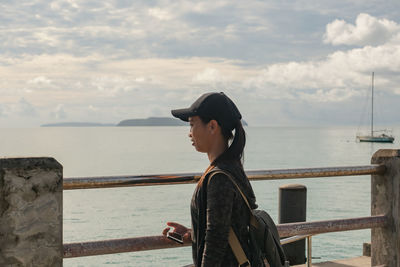 Side view of woman looking at sea against sky