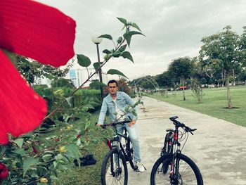 Portrait of young man riding bicycle on plants