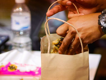 Close-up of hand holding drink on table