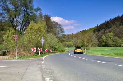 Car on road by trees against sky