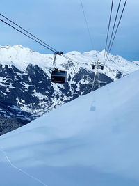 Ski lift over snowcapped mountains against sky