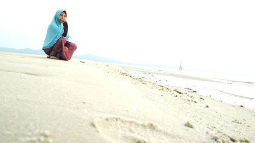 Woman crouching on shore at beach