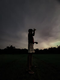 Man standing on field against sky during sunset