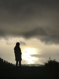 Rear view of silhouette man standing on land against sky during sunset