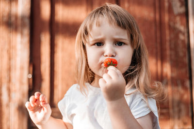 Portrait of cute girl eating strawberry