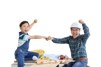 Full length of happy boy holding camera over white background