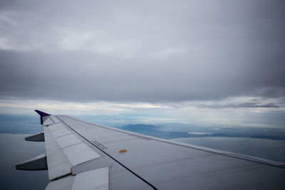 Cropped image of airplane wing flying against cloudscape