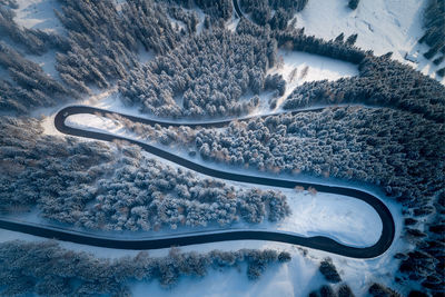 Aerial view of winding road amidst trees during winter