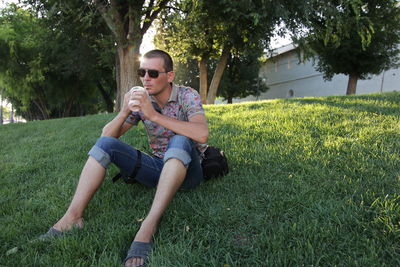 Full length of young man using phone while sitting on field