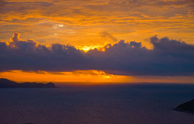 Scenic view of sea against dramatic sky during sunset